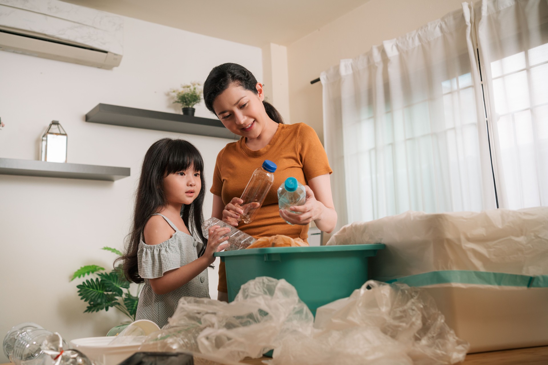 Mother teaching daughter sorting out waste for recycling recycle bank help climate change at home